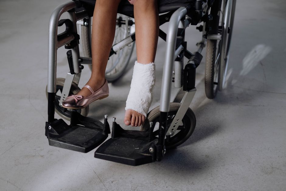 Acessibilidade Brasil — A close-up of a young girl's bandaged leg in a wheelchair, highlighting recovery.
