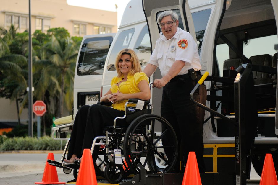 Acessibilidade Brasil — A transport service assisting a person in a wheelchair outdoors, focusing on accessibility.