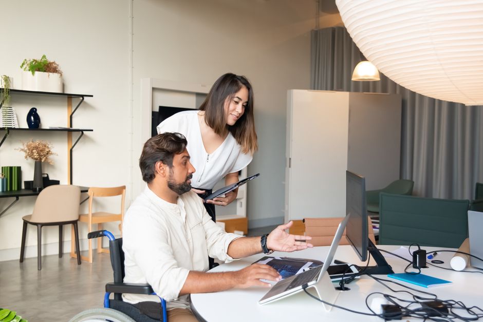 Acessibilidade Brasil — Diverse coworkers collaborating on a project in a modern office space with accessible facilities.