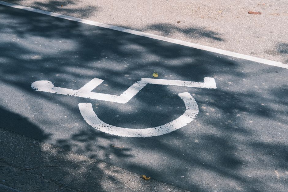 Acessibilidade Brasil — Close-up of an accessible parking symbol on a sunlit asphalt road.