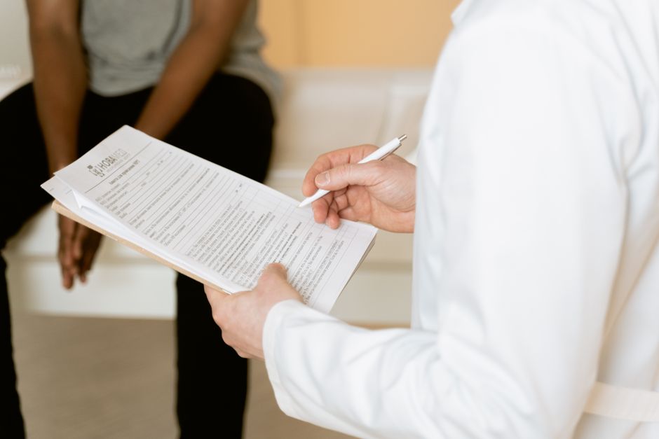 Acessibilidade Brasil — Healthcare professional reviews medical form during patient consultation in a clinic setting.